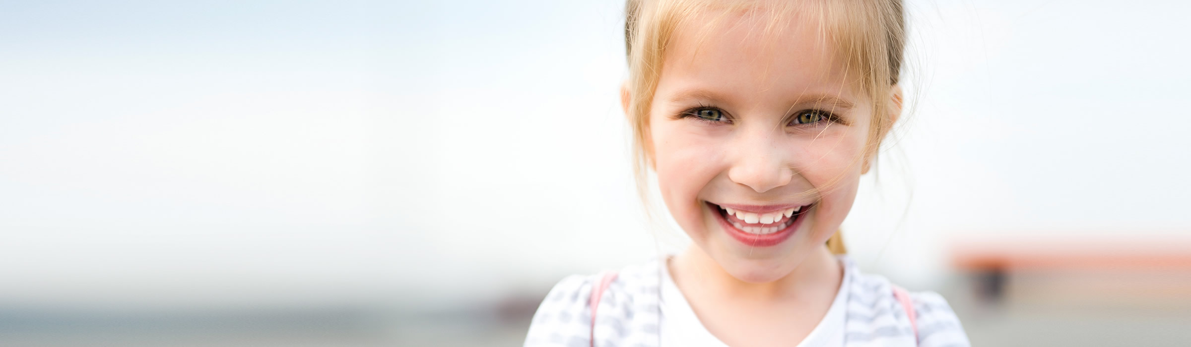 Child in white smiling at our Watford dentist, Senova Dental Studios in Watford, Hertfordshire