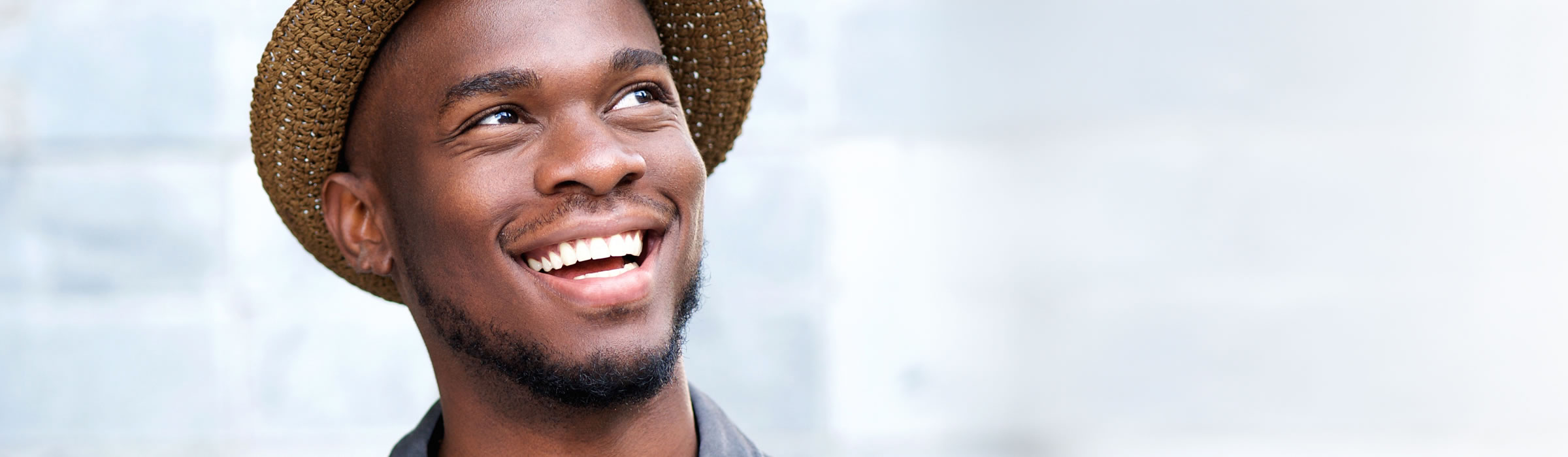 Young man wearing hat smiling. Dental implant gallery for our Watford dentist, Senova Dental Studios in Hertfordshire